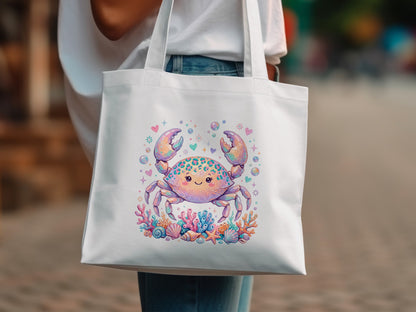 White tote bag with cartoon crab design, surrounded by coral and seashells.