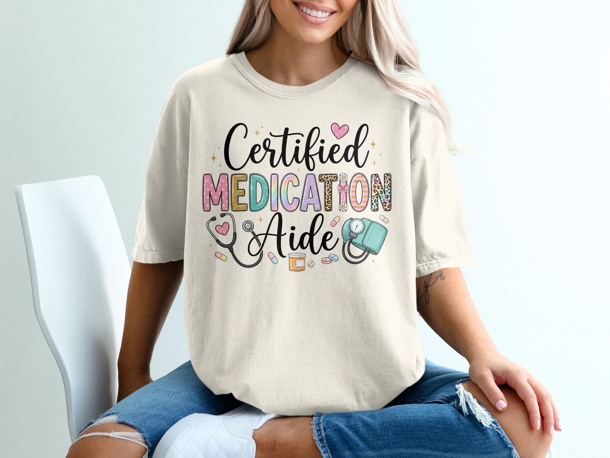 Cream t-shirt with "Certified Medication Aide" text and medical icons.