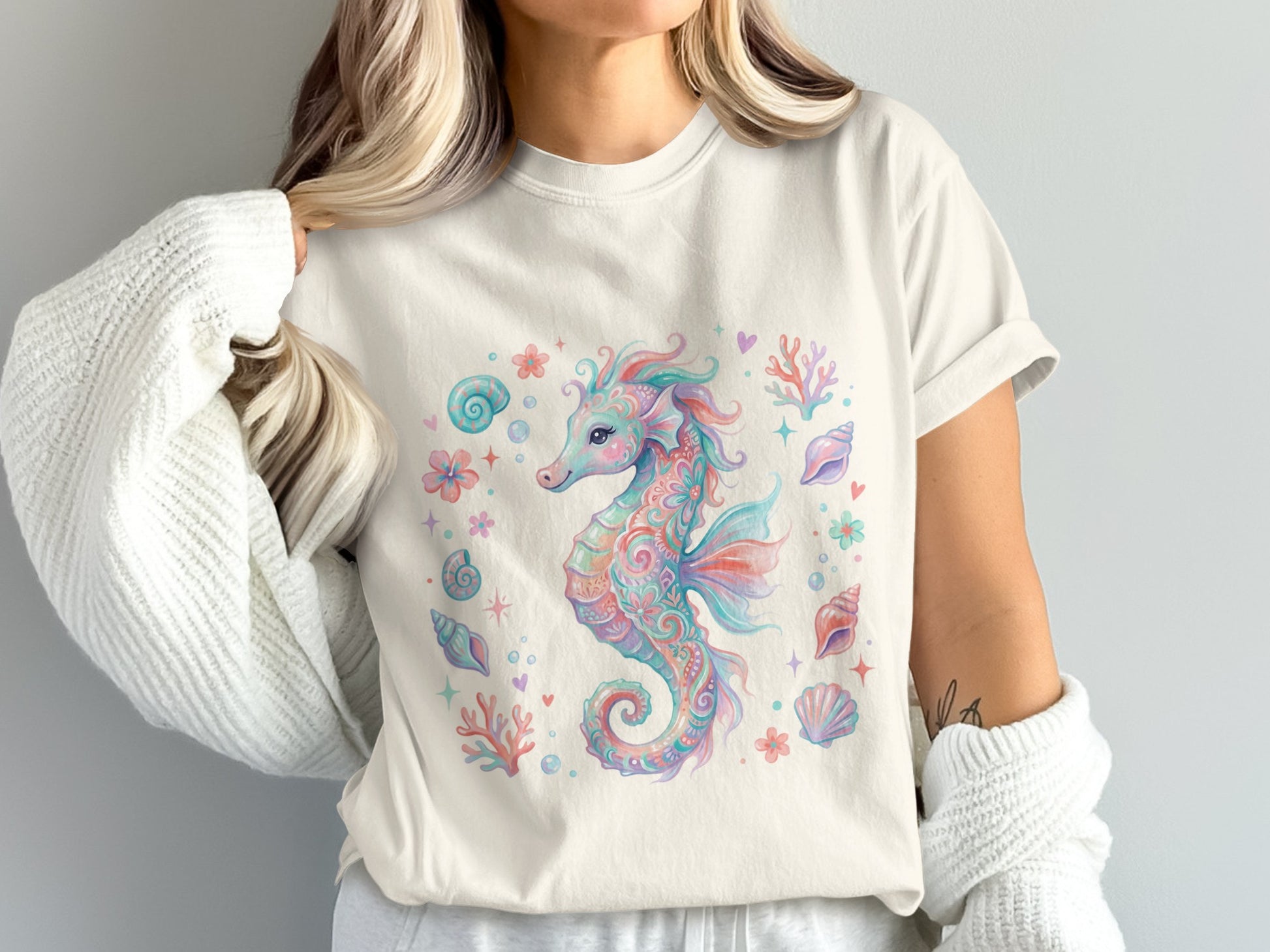 Cream t-shirt with a watercolor seahorse and seashells pattern.