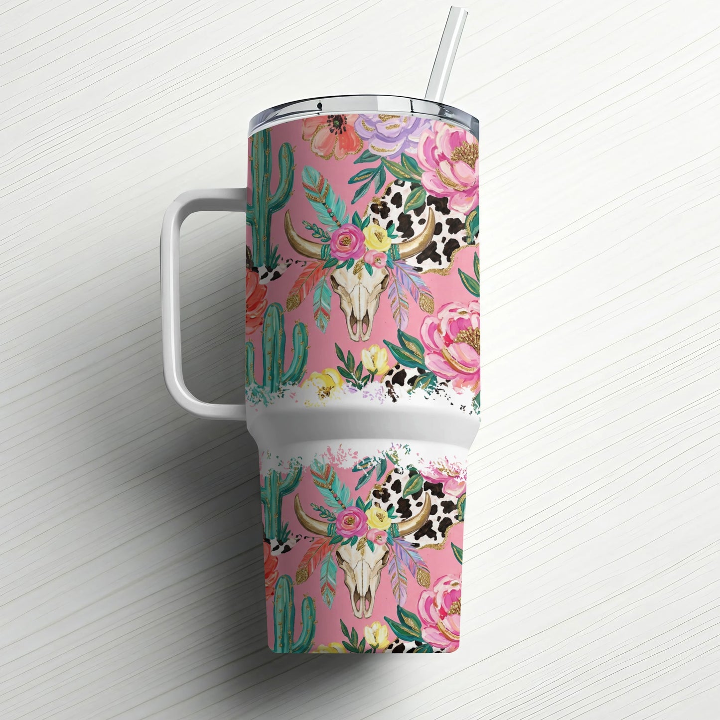 Pink tumbler with cow skull, cactus, and floral pattern, white handle and straw.