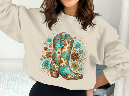 Turquoise cowboy boot with floral accents, on a cream sweatshirt.