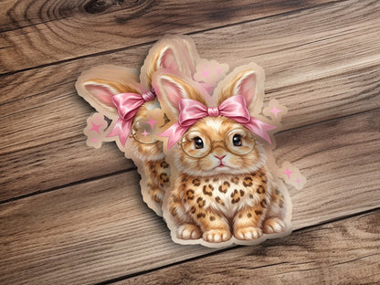 Two cute bunnies with glasses and pink bows on wooden background.