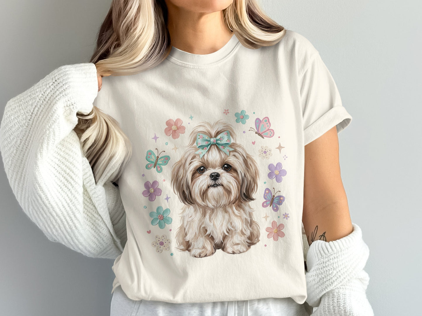Cream t-shirt with cartoon Shih Tzu dog wearing a blue bow surrounded by butterflies and flowers.