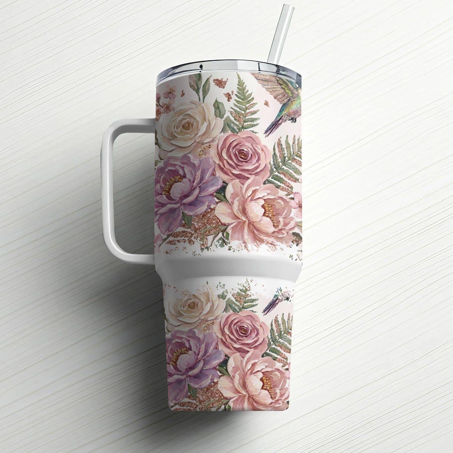 Floral tumbler with hummingbirds and ferns, featuring a straw.