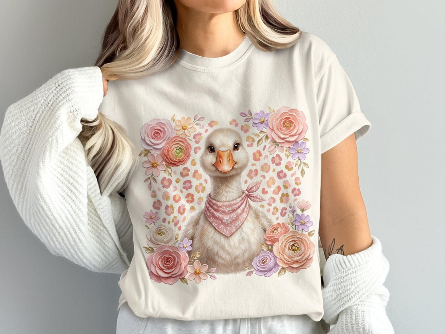 Cream t-shirt with a cartoon duck wearing a pink bandana, surrounded by flowers.