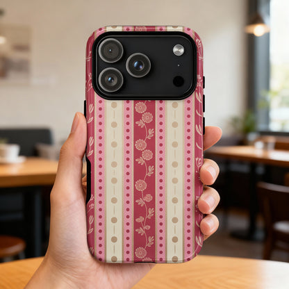 iPhone 14 Pro case with a pink and cream floral stripe pattern held in a hand.