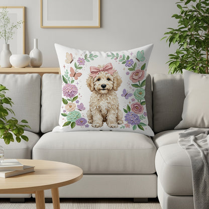 Fluffy golden doodle puppy with a pink bow sits on a pillow surrounded by flowers and butterflies.