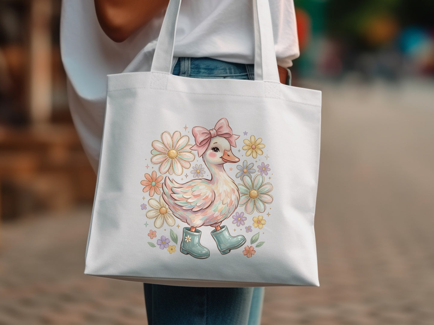 White tote bag with a duckling wearing boots surrounded by daisies and flowers.