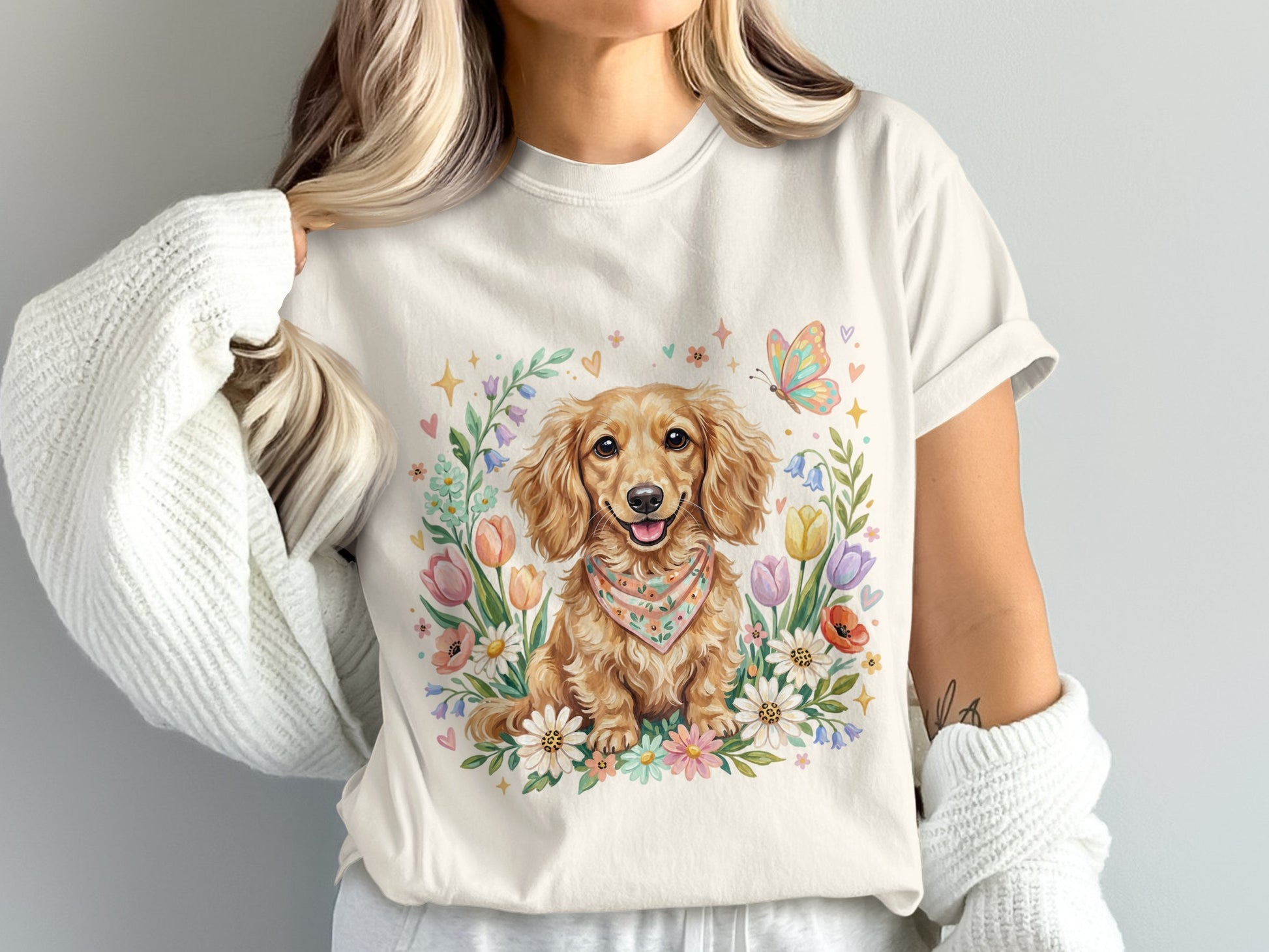 Cream t-shirt with a watercolor dachshund wearing a bandana surrounded by flowers and butterflies.