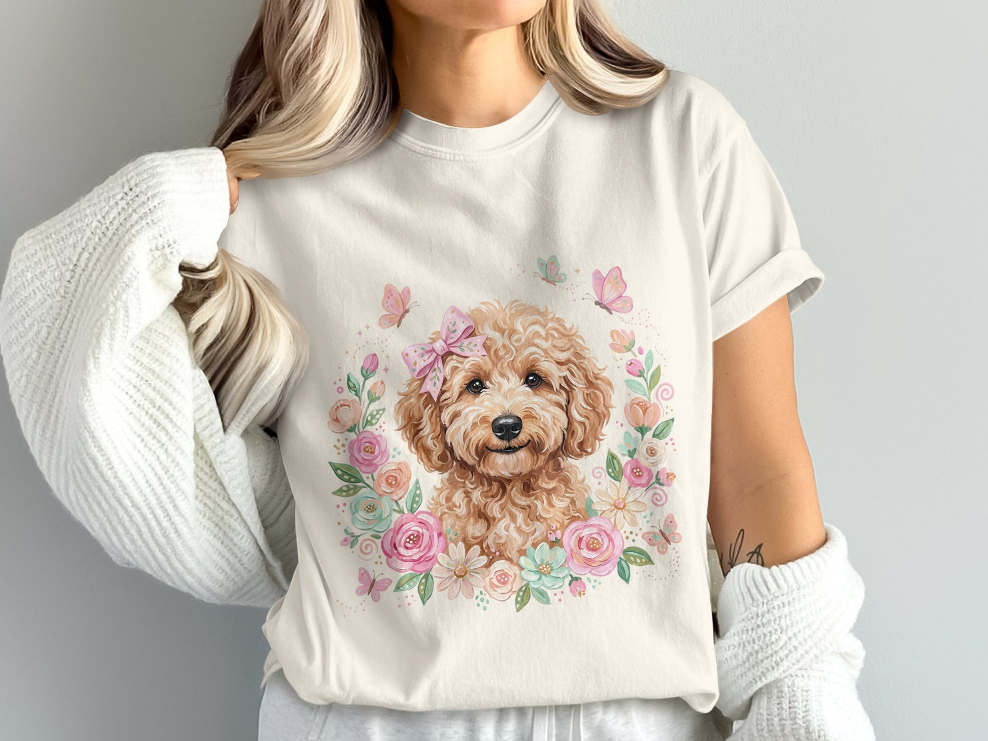 Cream t-shirt with a watercolor doodle dog surrounded by flowers and butterflies.