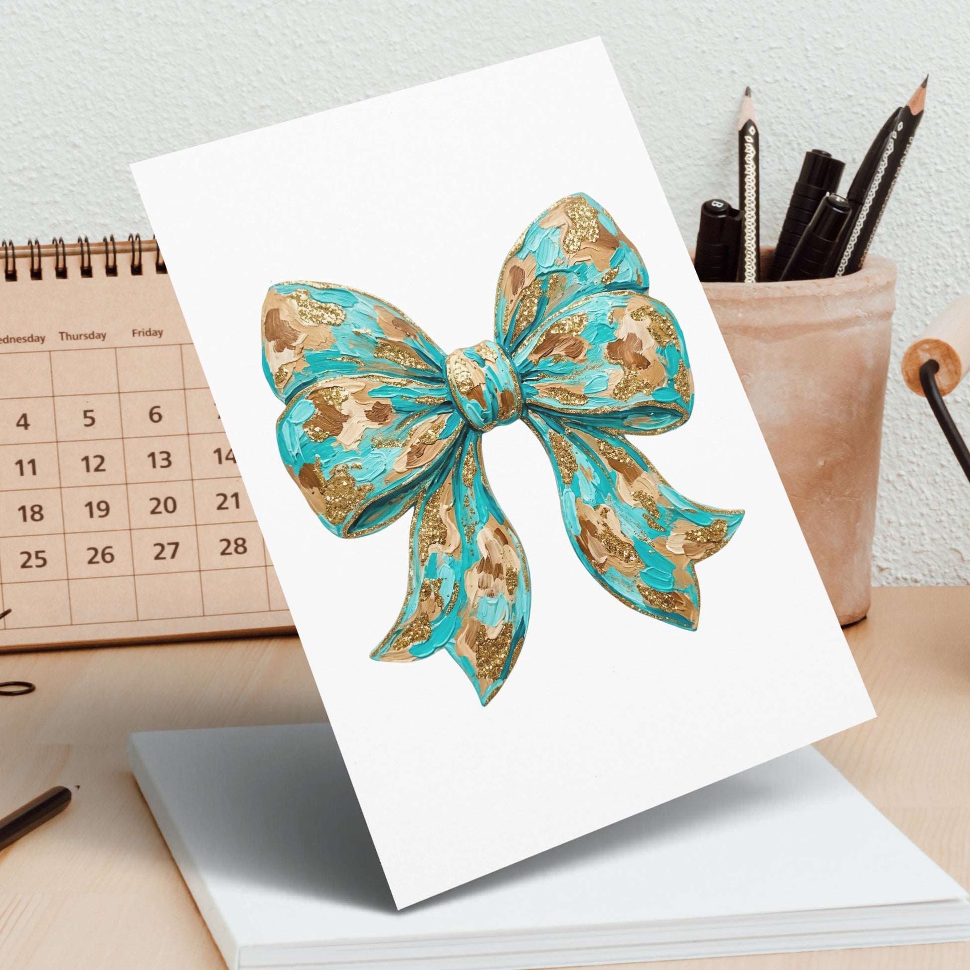 Turquoise and gold textured bow on a white card, desk background.