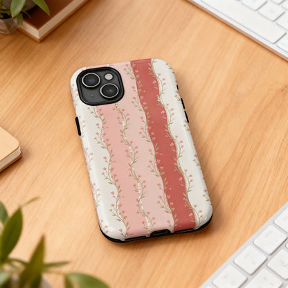 Floral phone case with pink and cream stripes on wooden surface.