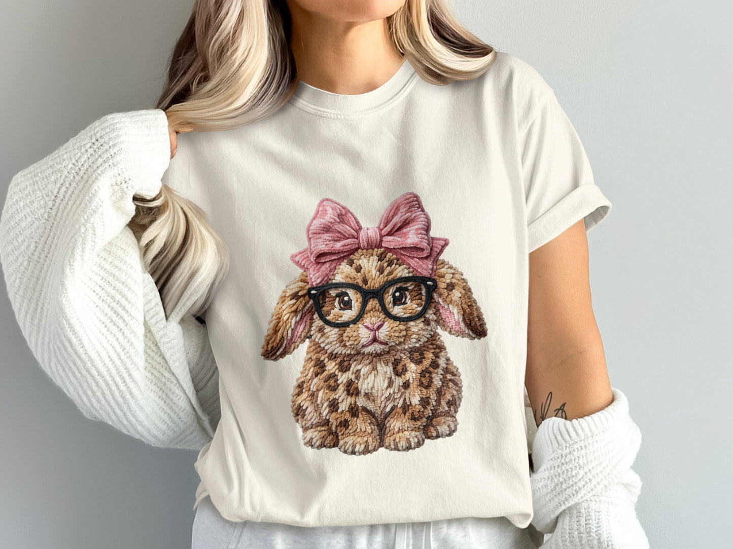 Cream t-shirt with a watercolor print of a leopard-patterned bunny wearing glasses and a pink bow.