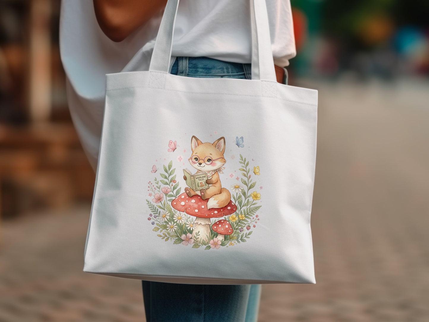 White tote bag with watercolor illustration of a fox reading on a mushroom.