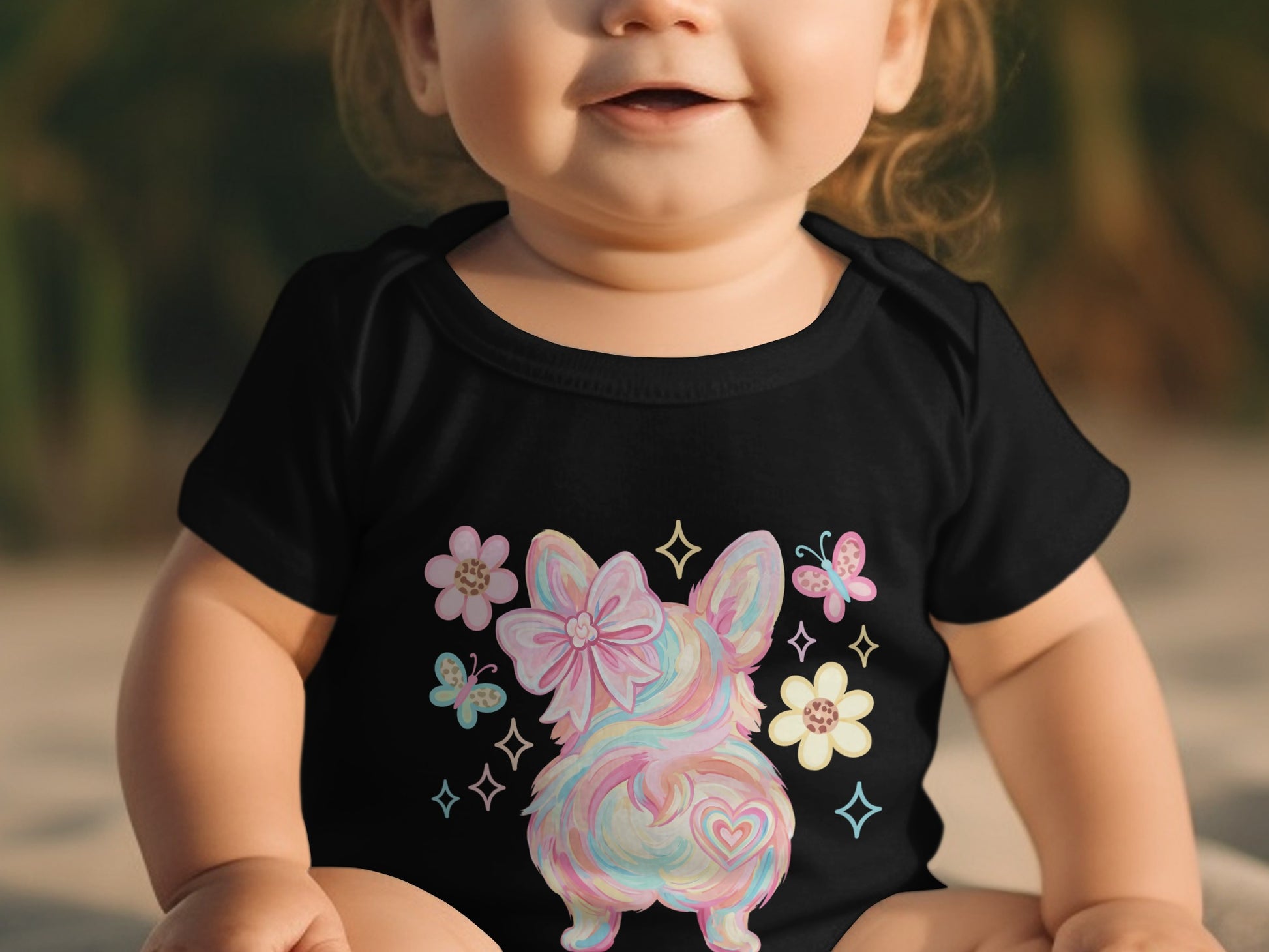 Baby wearing black onesie with pastel puppy, bow, and butterflies.