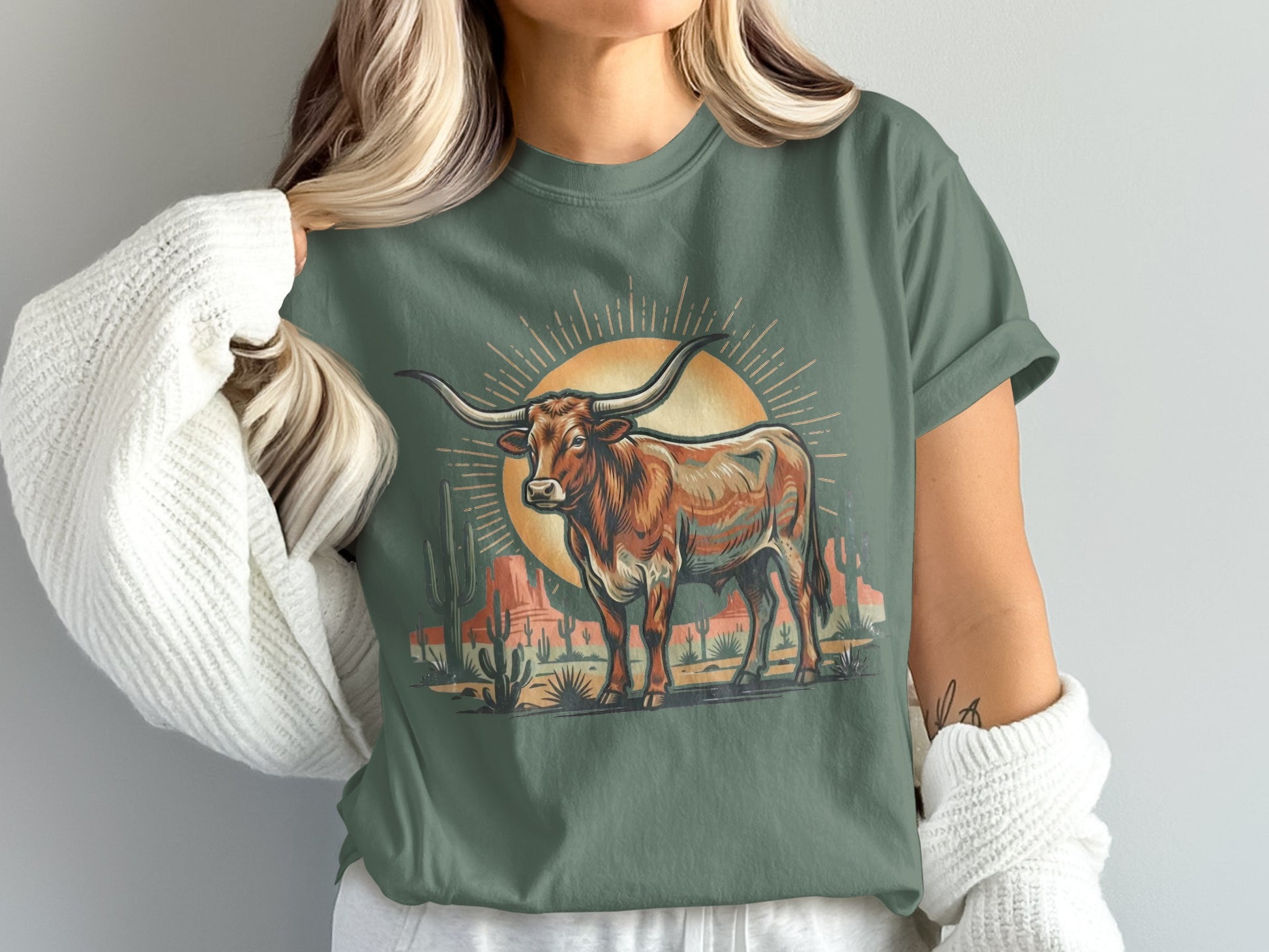 Longhorn bull with sun and desert landscape graphic on a green t-shirt.
