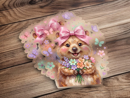 Fuzzy cartoon animal with pink bows holding a bouquet of flowers.