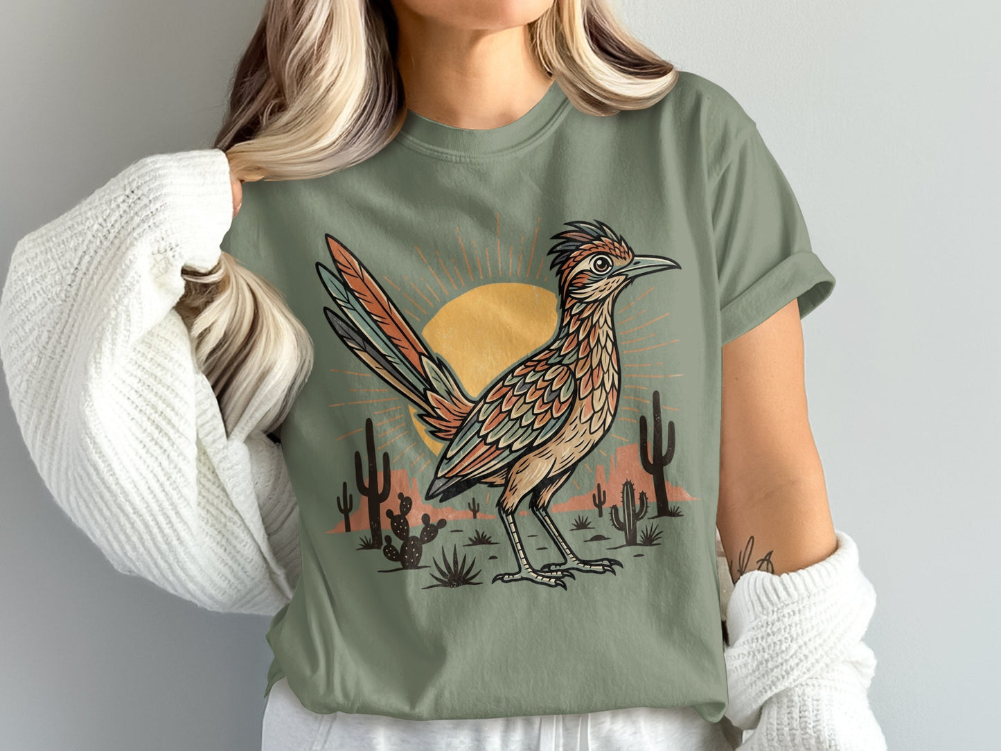 Roadrunner with desert landscape and sun graphic on green t-shirt.