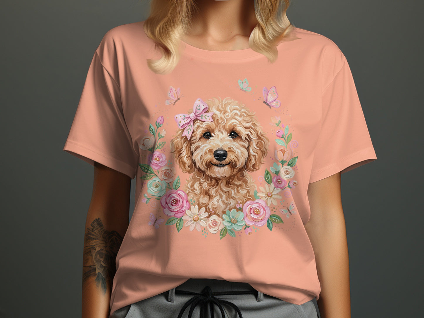 Peach t-shirt featuring a fluffy dog adorned with a bow surrounded by flowers and butterflies.