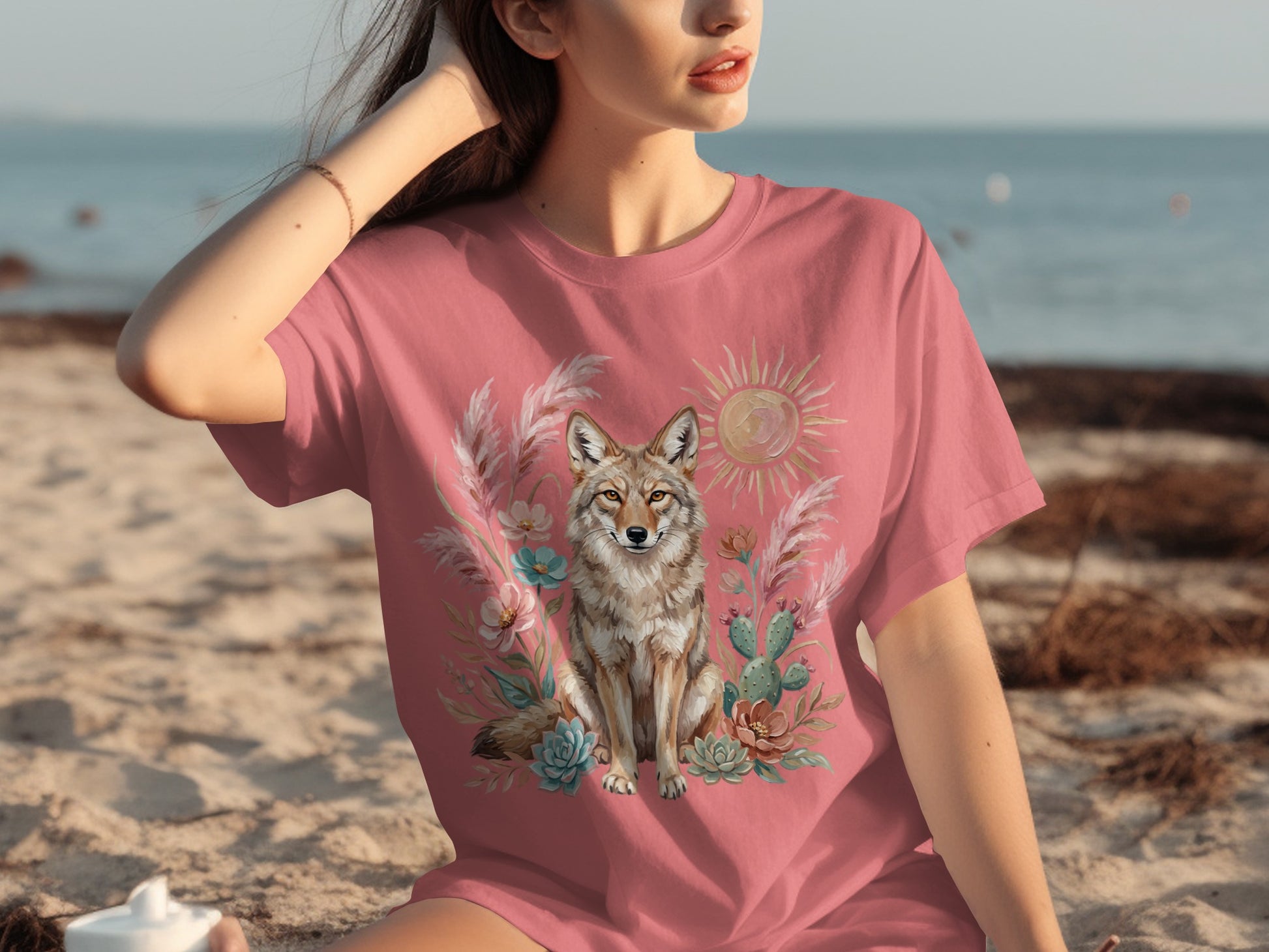 Coral t-shirt with a desert scene featuring a coyote, cactus, and sun.