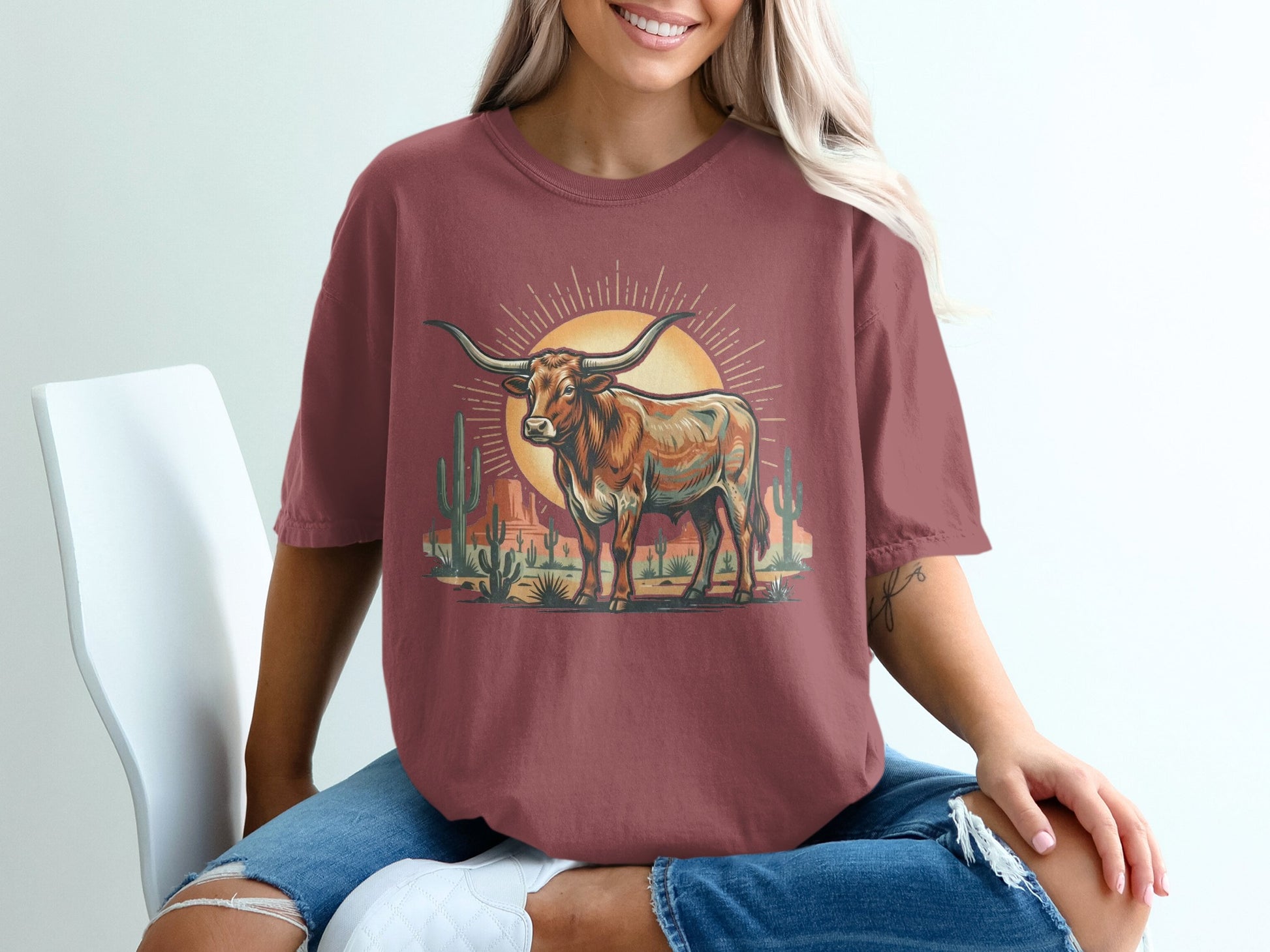 T-shirt graphic with a longhorn bull in a desert landscape with cacti and sun.