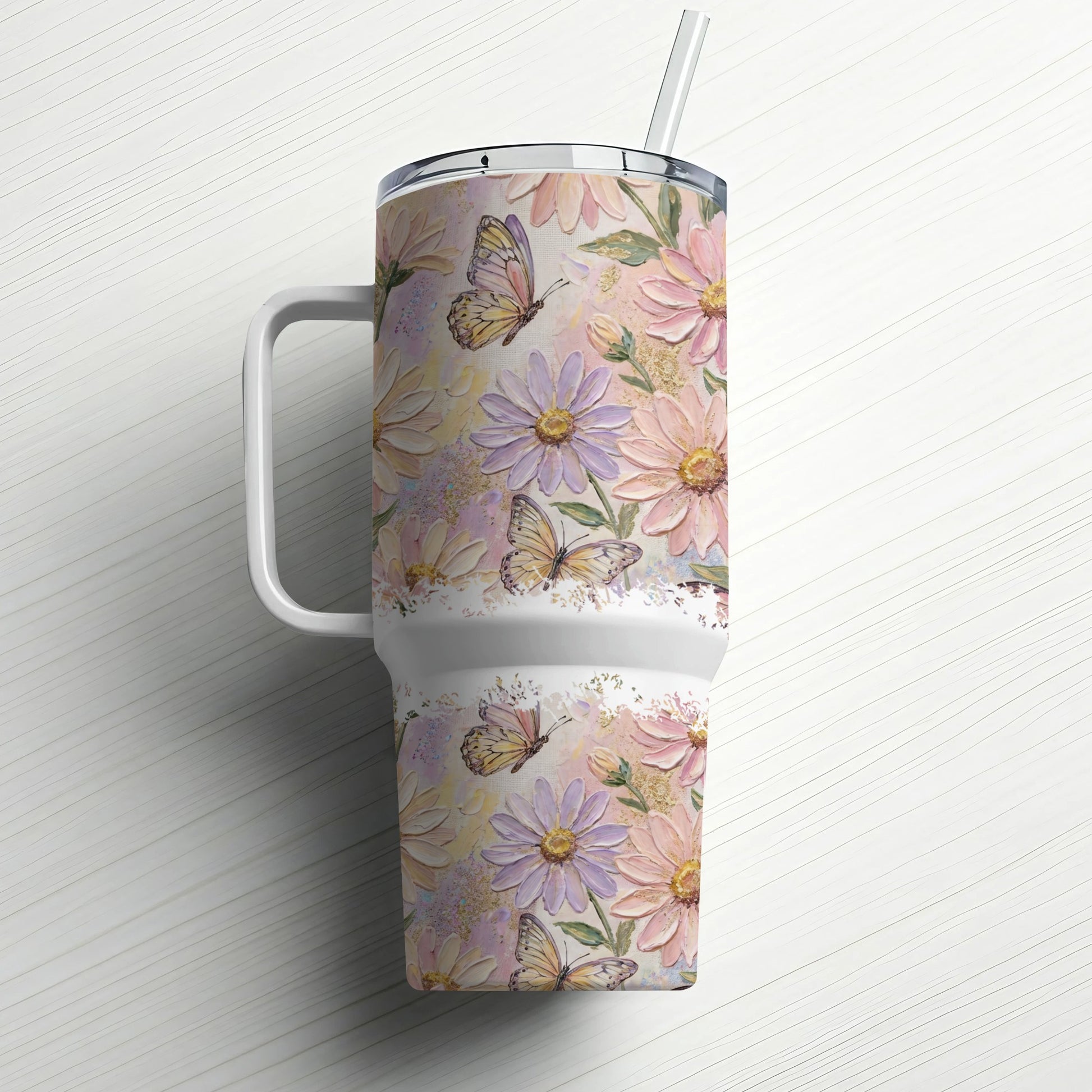 Floral tumbler with butterflies and straw, on a white wood surface.