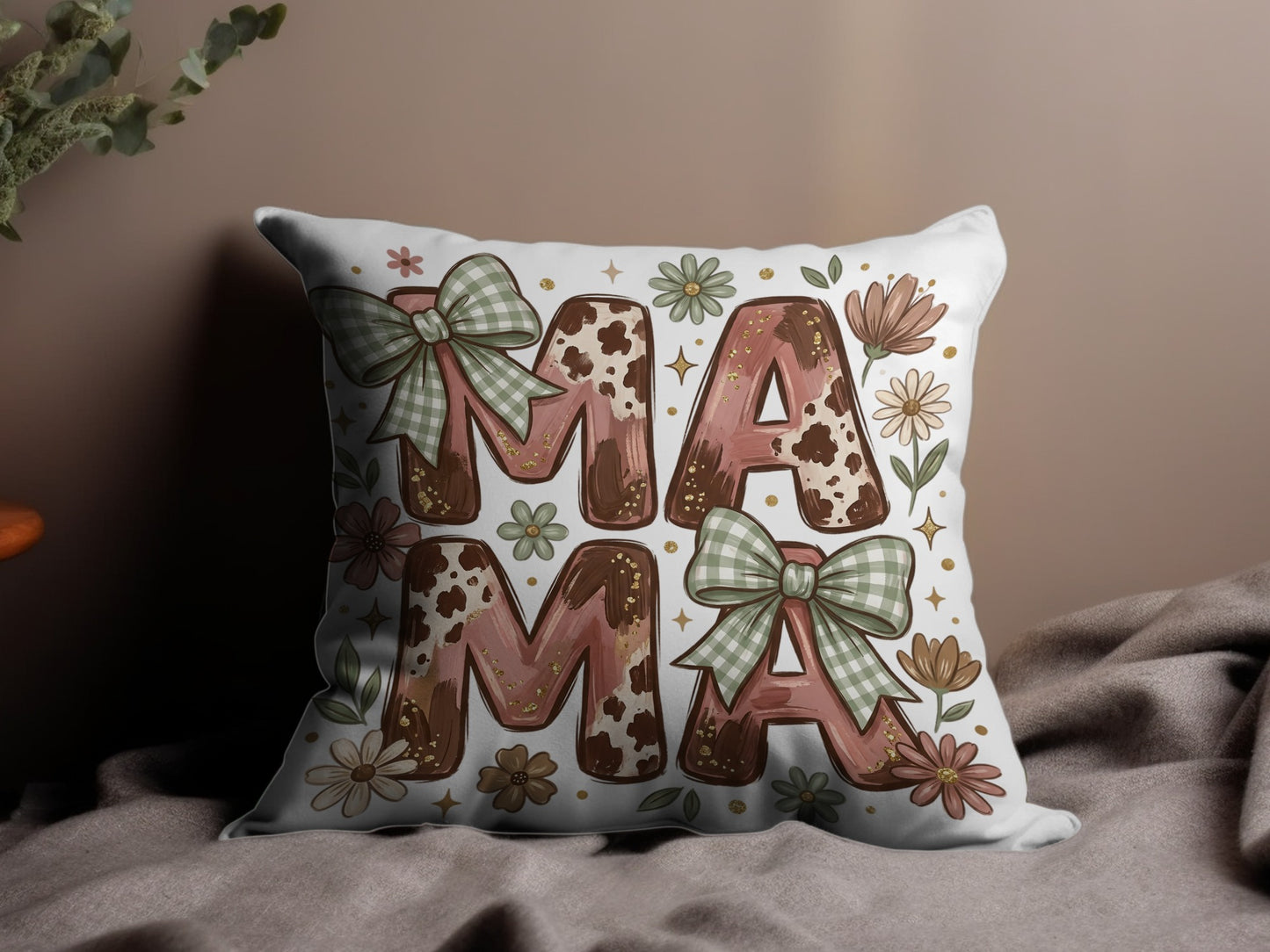 Pillow with "MAMA" text in cow print and floral design with green bows.