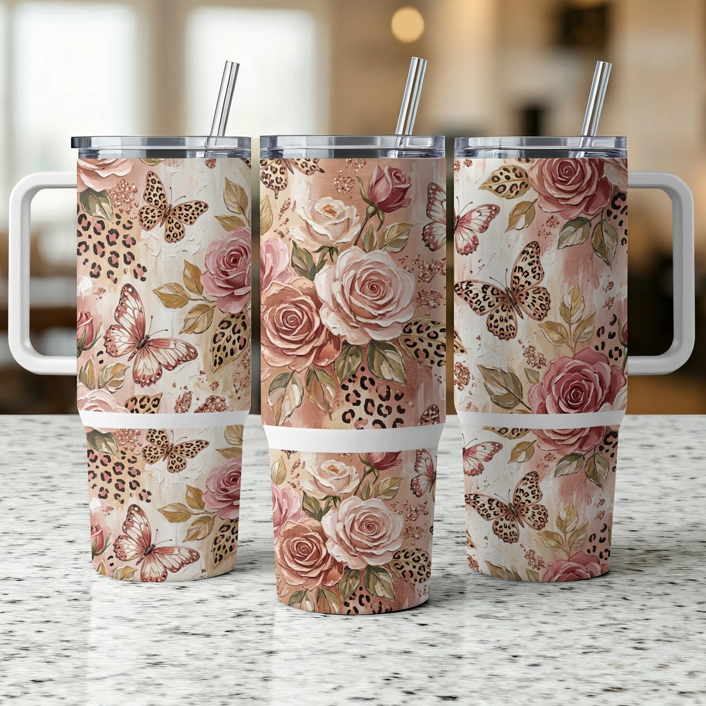 Three floral and butterfly tumblers with handles and straws on a counter.