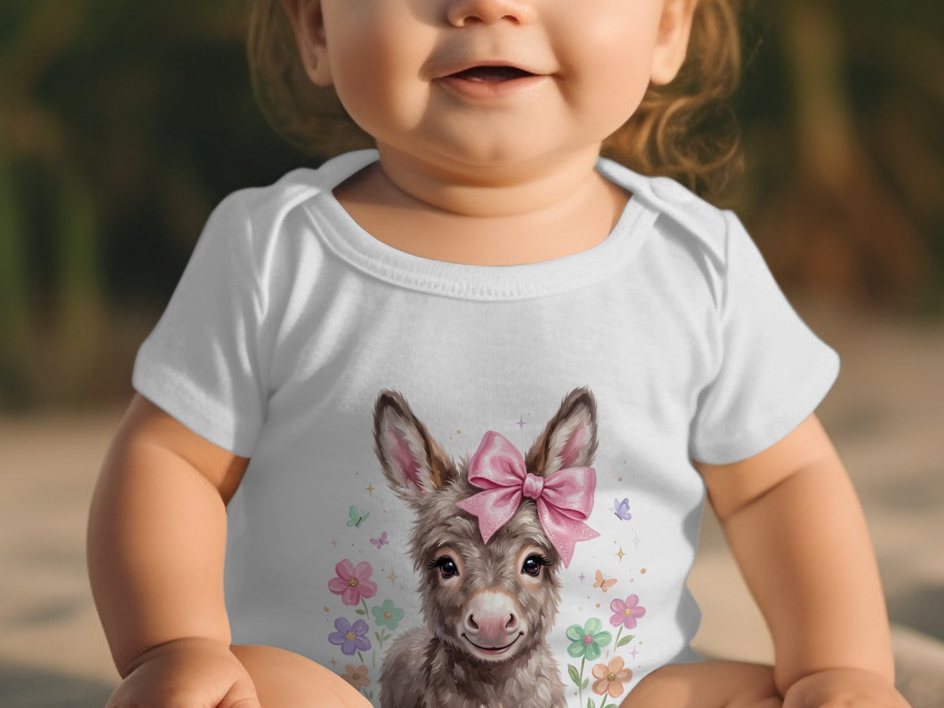 Baby wearing white bodysuit with a donkey and flowers graphic.