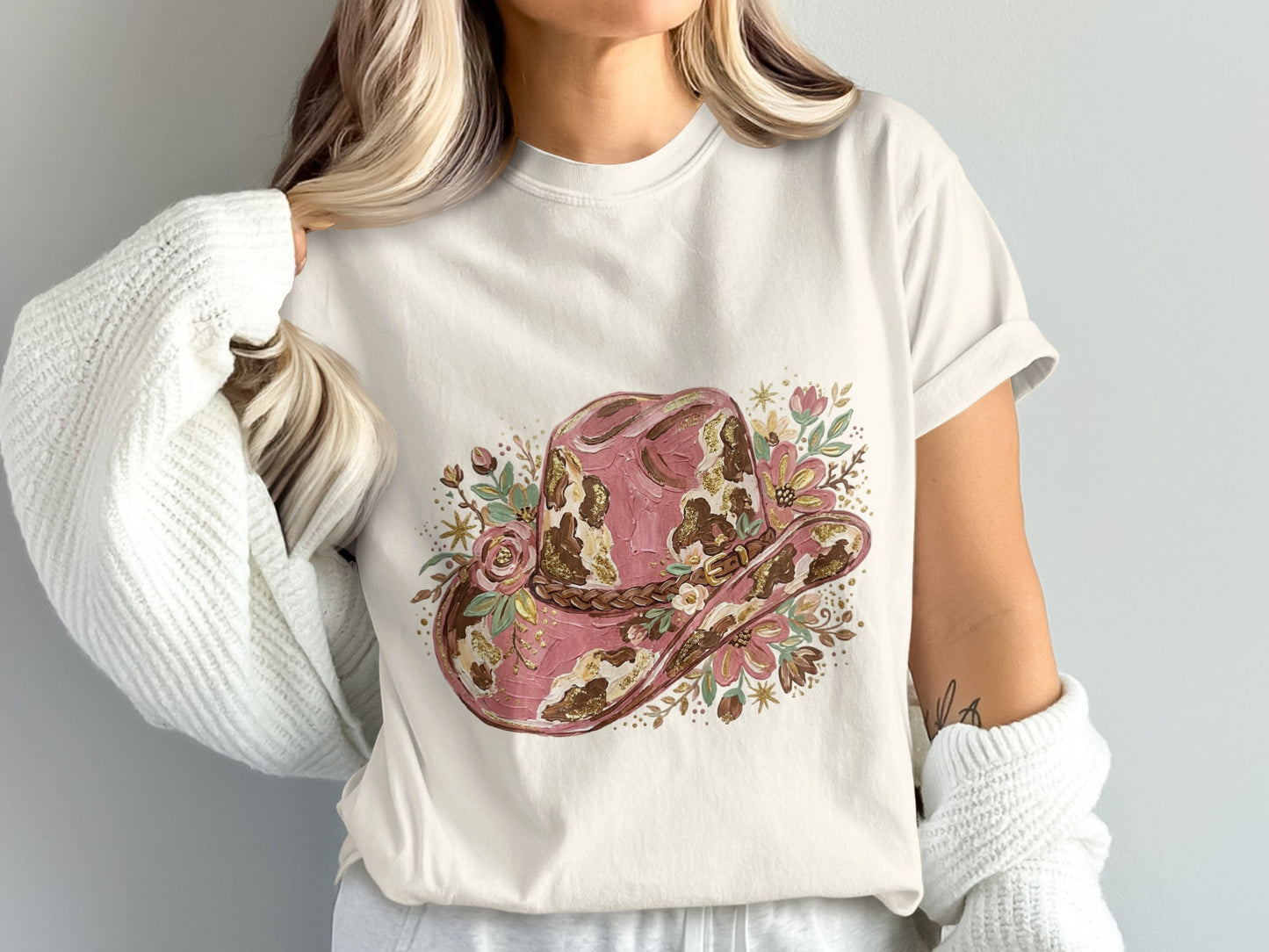 White t-shirt with a distressed pink cowboy hat graphic featuring floral accents.