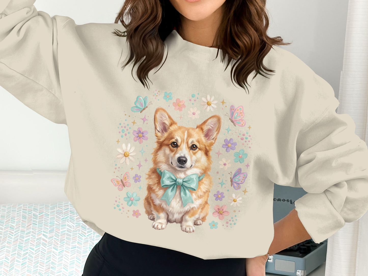 Cream sweatshirt with a Corgi wearing a blue bow and surrounded by flowers and butterflies.