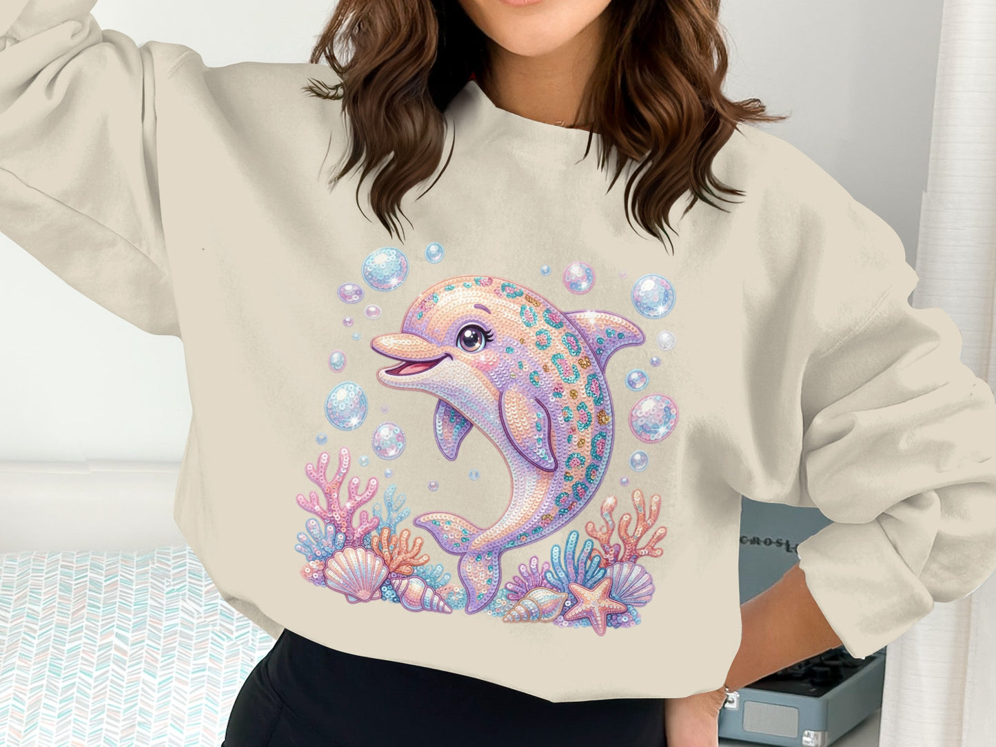 Cream sweatshirt with a smiling dolphin and underwater coral reef illustration.