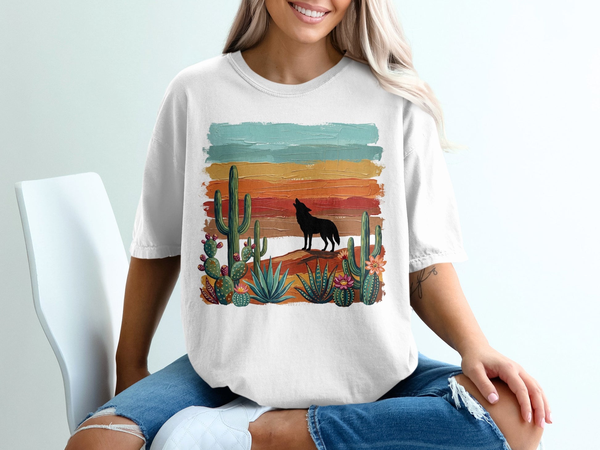White t-shirt with silhouette of wolf howling at sunset over desert landscape.