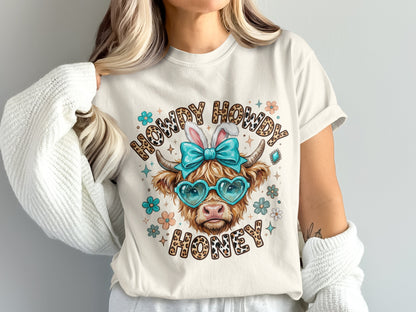 Cow with bunny ears and heart sunglasses, wearing a shirt that says "Howdy Howdy Honey."