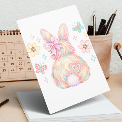 Fluffy bunny illustration with pastel colors and butterflies on a desk.