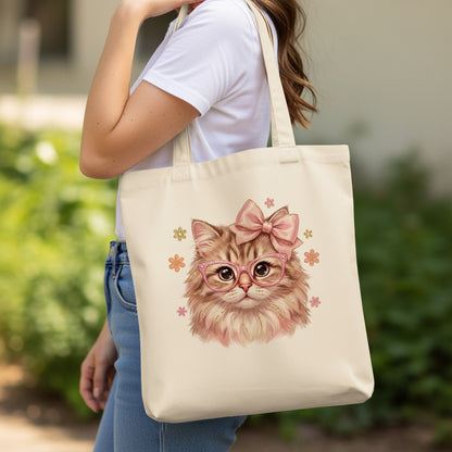 Beige tote bag with pink cat illustration wearing glasses and a bow.