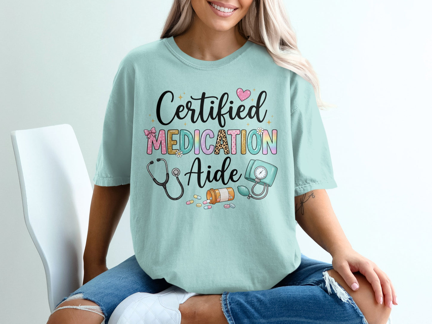 Certified Medication Aide text with stethoscope and medical supplies on light blue t-shirt.