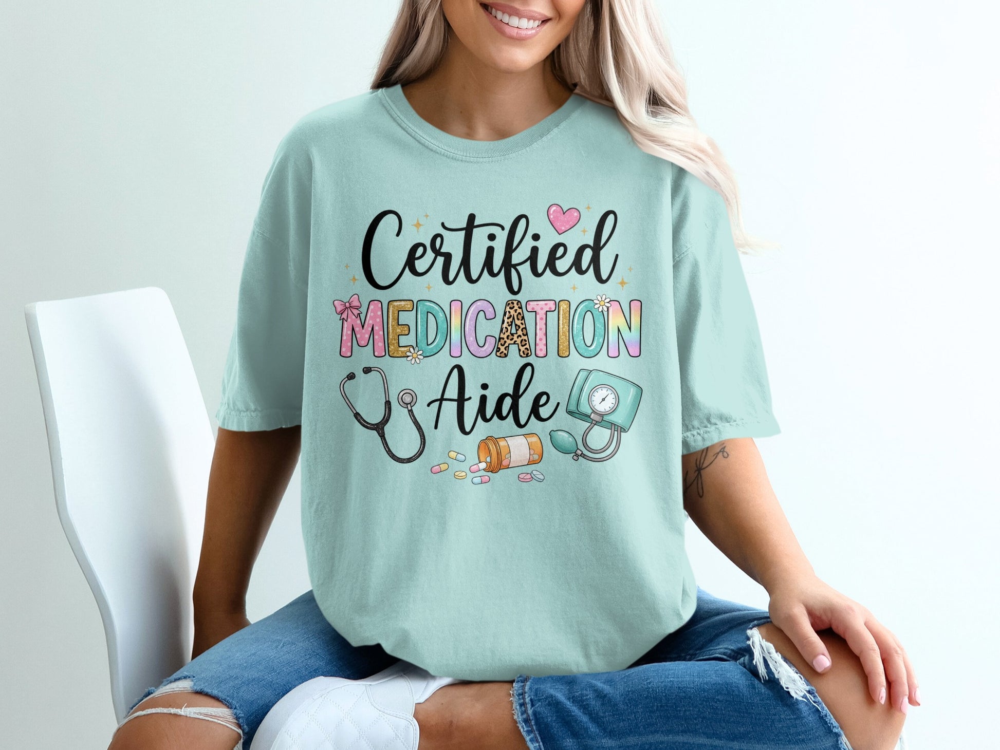 Certified Medication Aide text with stethoscope and medical supplies on light blue t-shirt.