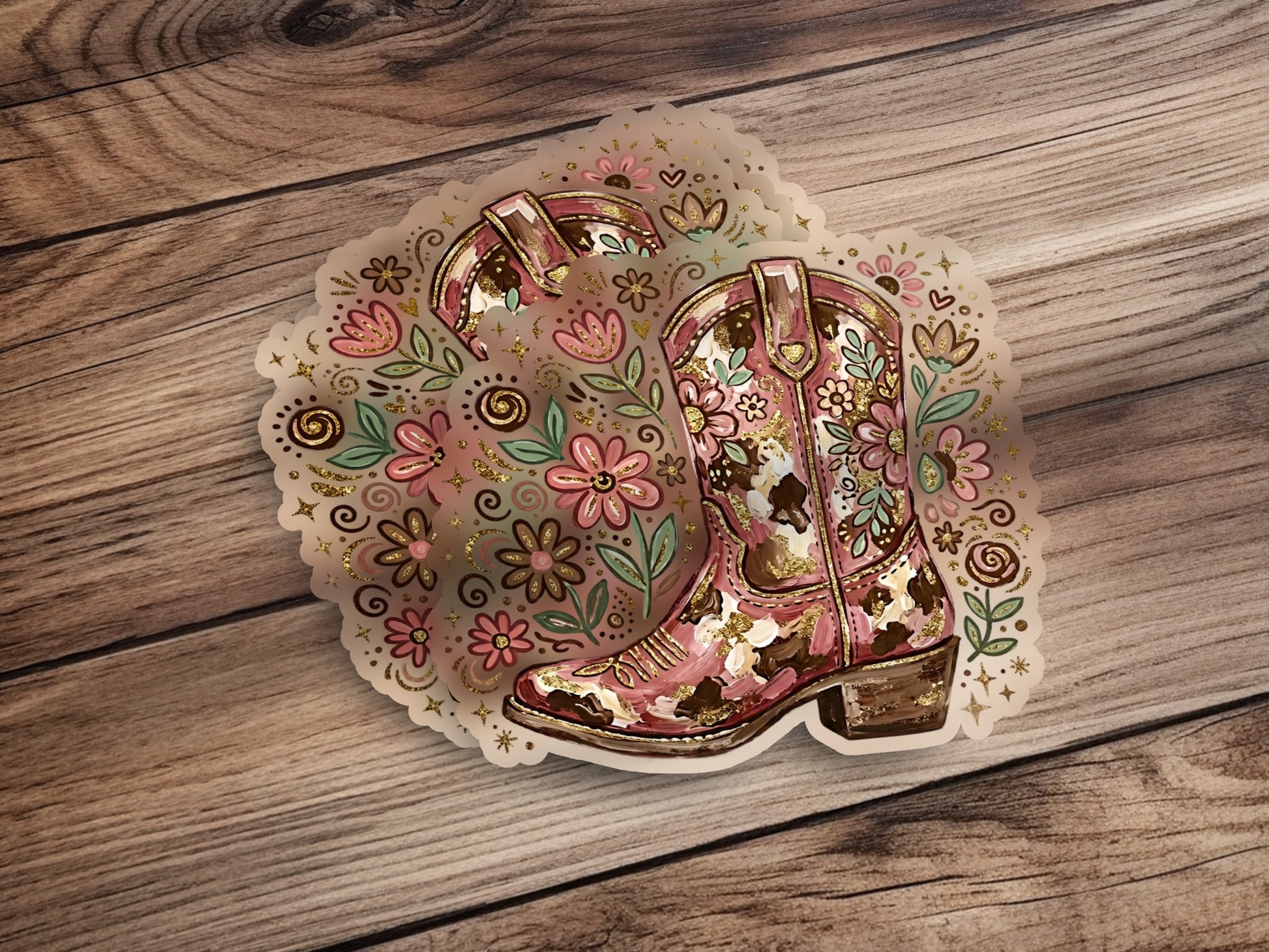 Pink and gold floral cowboy boot sticker on a wooden background.