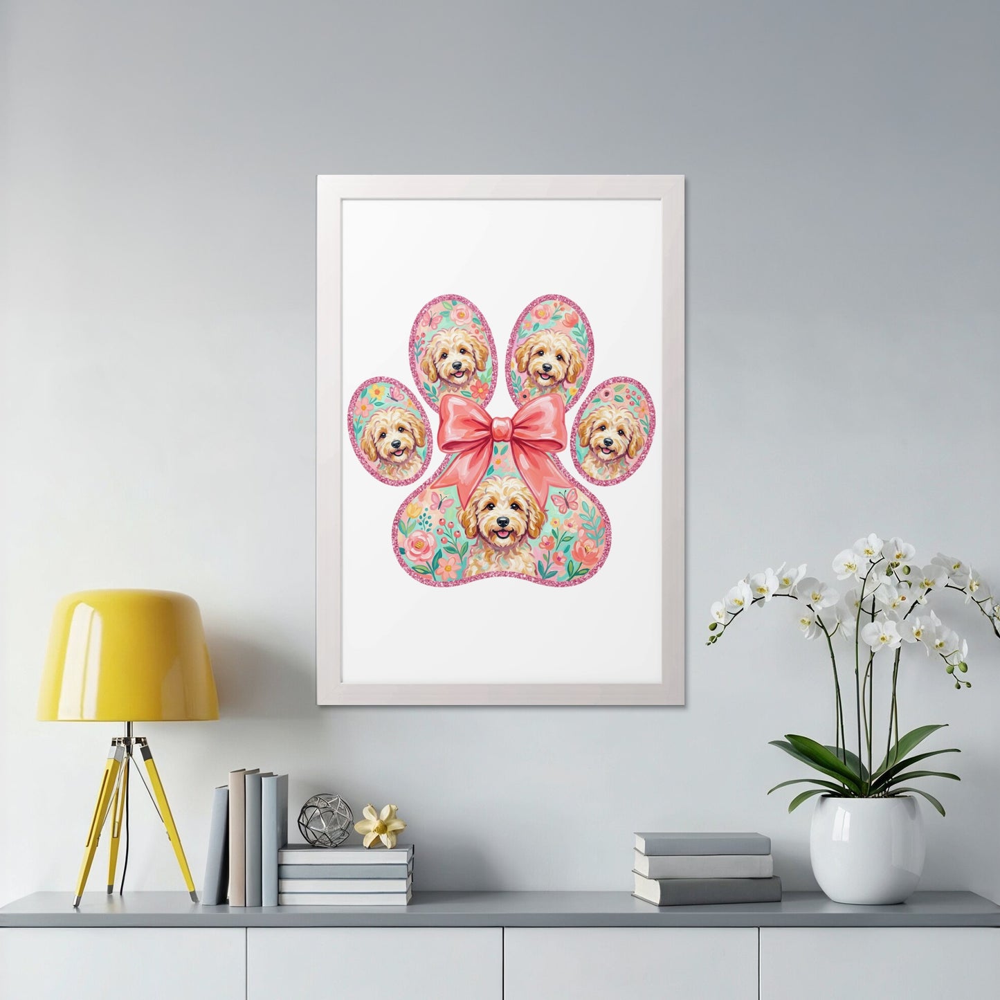 Framed print of a paw with dog faces and floral accents, tied with a pink bow.