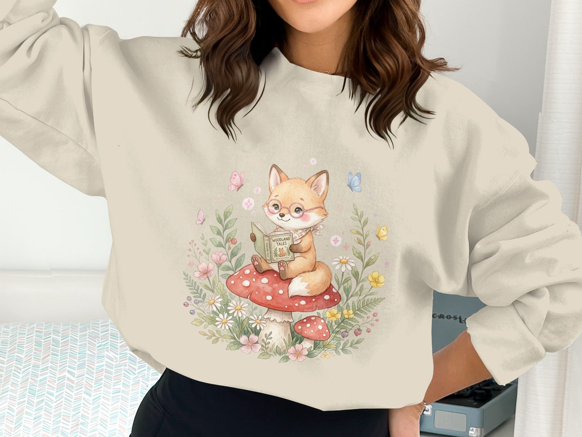 Sweatshirt with a fox reading a book on a mushroom, surrounded by flowers.