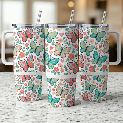 Three tumblers with colorful butterfly and flower patterns and reusable straws.