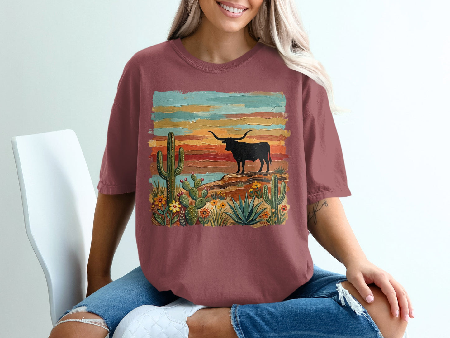 Longhorn and cactus desert scene on a maroon graphic t-shirt.