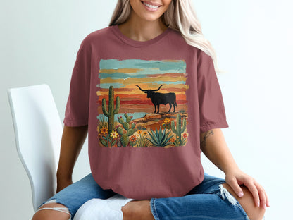 Longhorn and cactus desert scene on a maroon graphic t-shirt.