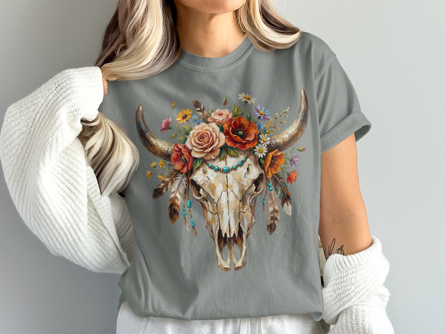Skull with flowers and turquoise necklace, worn by a person in a white cardigan.