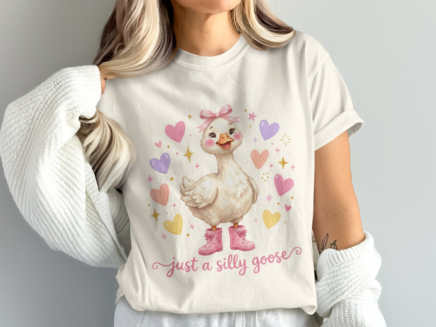 White t-shirt with a cartoon goose wearing pink boots and text "just a silly goose."