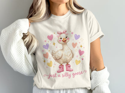 White t-shirt with a cartoon goose wearing pink boots and text "just a silly goose."