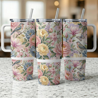 Three floral tumblers with birds and butterflies on a speckled countertop.