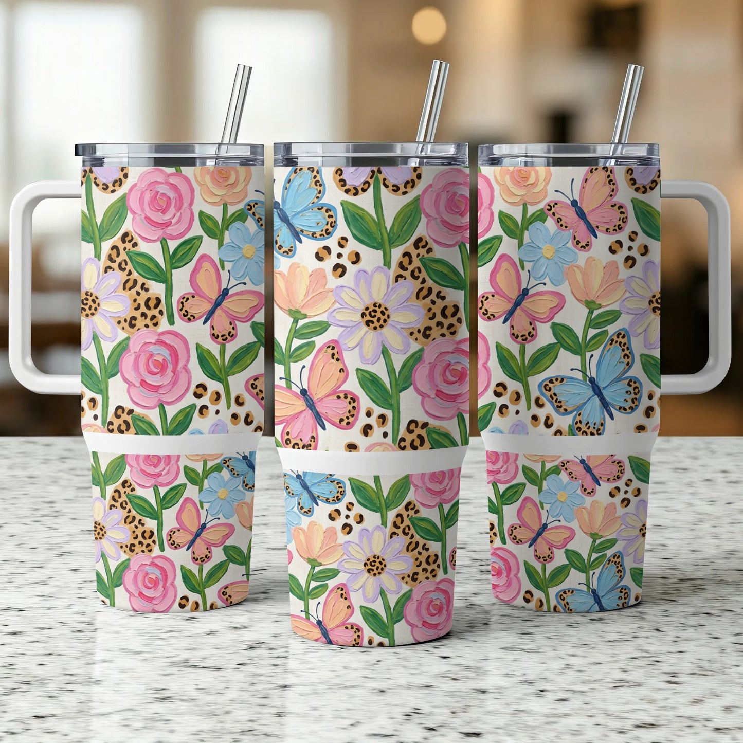 Three tumblers with floral and butterfly pattern, each with a handle and straw.