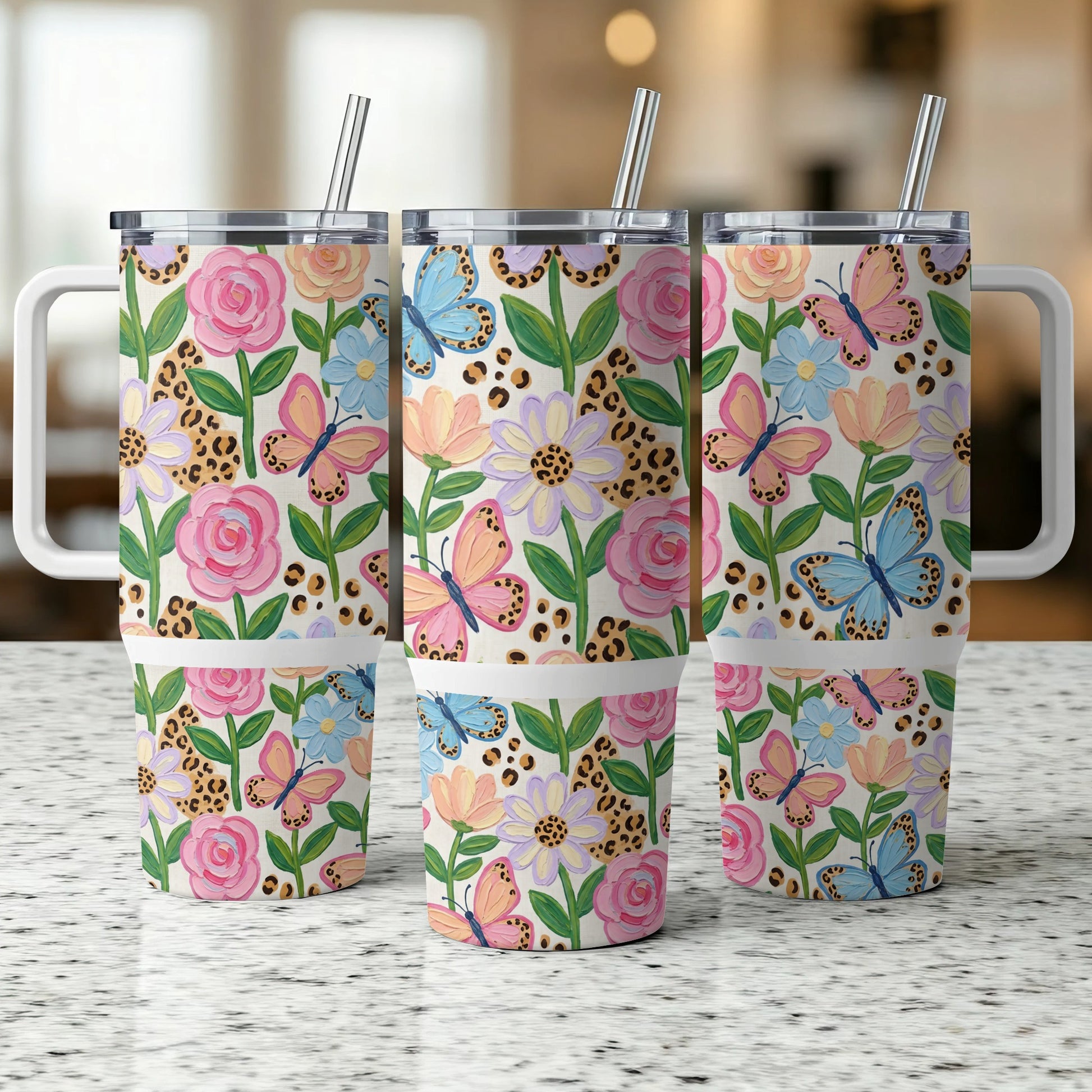 Three tumblers with floral and butterfly pattern, each with a handle and straw.